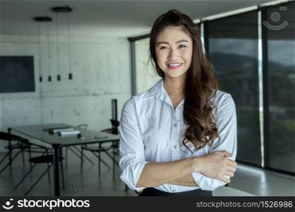 Business Asian woman wearing white shirt smile and cross arm in modern office,Business and Startup Concept