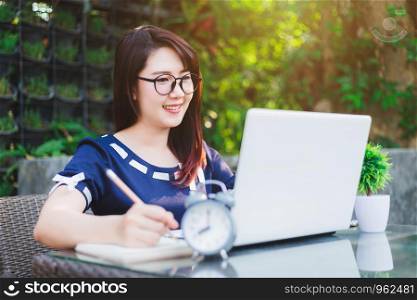 Business Asian woman working with make a note,laptop computer and clock on office outdoor.