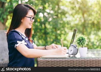 Business Asian woman working with make a note,laptop computer and clock on office outdoor.