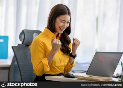 Business Asian young woman celebrating with laptop after success job feeling so happy and cheerful,Small Business Startup concept 