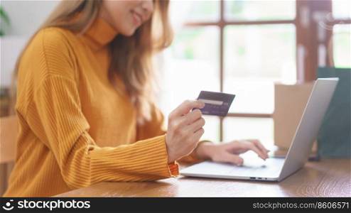 Business at home concept, Young Asian woman is typing credit card data on laptop to shopping online.