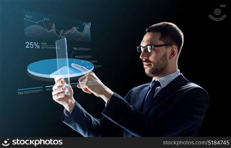 business, augmented reality and future technology concept - businessman in glasses working with transparent tablet pc computer and virtual charts projections over black background. businessman with tablet pc and virtual charts
