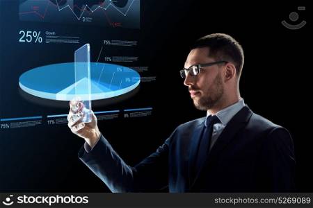 business, augmented reality and future technology concept - businessman in glasses working with transparent tablet pc computer and virtual charts projections over black background. businessman with tablet pc and virtual charts