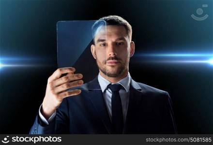 business, augmented reality and future technology concept - businessman in suit working with transparent tablet pc computer over black background. businessman working with transparent tablet pc
