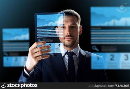 business, augmented reality and future technology concept - businessman in suit working with transparent tablet pc computer and virtual exchange charts projections over black background. businessman with tablet pc and exchange charts