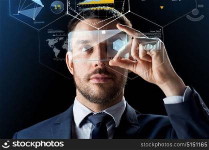 business, augmented reality and future technology concept - businessman working with transparent smartphone and virtual screens projections over black background. businessman with smartphone and virtual holograms