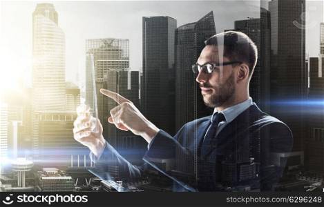 business, augmented reality and modern technology concept - businessman in glasses working with transparent tablet pc computer over city buildings background and double exposure effect. businessman working with transparent tablet pc