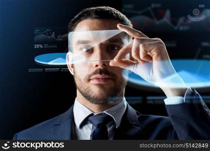 business, augmented reality and modern technology concept - businessman working with transparent smartphone and virtual charts projections over black background. businessman with smartphone and virtual charts