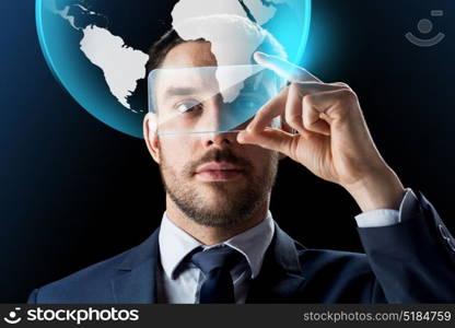 business, augmented reality and modern technology concept - businessman working with transparent smartphone and virtual earth globe hologram over black background. businessman with smartphone and virtual globe