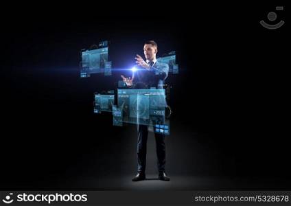 business, augmented reality, people and future technology concept - businessman in suit working with virtual screens projection over black background. businessman in suit with virtual projection