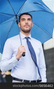 business, bad weather and people and concept - young serious businessman with umbrella outdoors