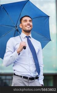 business, bad weather and people and concept - young smiling businessman with umbrella outdoors