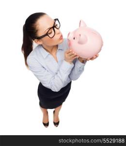business, banking, investment and office concept - laughing businesswoman in eyeglasses sendink kisses to piggy bank