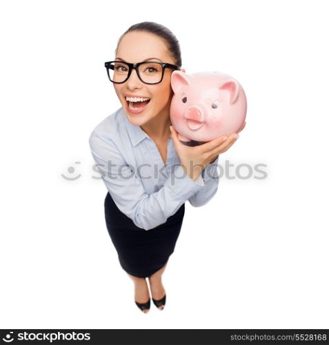business, banking, investment and office concept - laughing businesswoman in eyeglasses with piggy bank