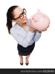 business, banking, investment and office concept - smiling businesswoman in eyeglasses with piggy bank
