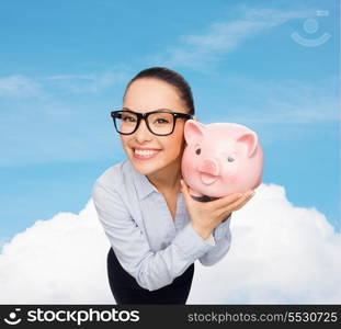 business, banking, investment and office concept - smiling businesswoman in eyeglasses with piggy bank