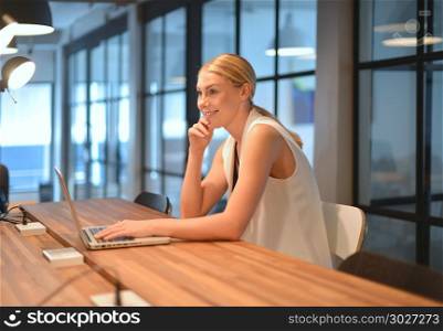 Business blonde girl using a laptop in an office