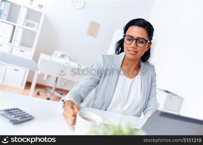 business, break and people concept - smiling businesswoman drinking coffee or tea at office. businesswoman drinking coffee or tea at office