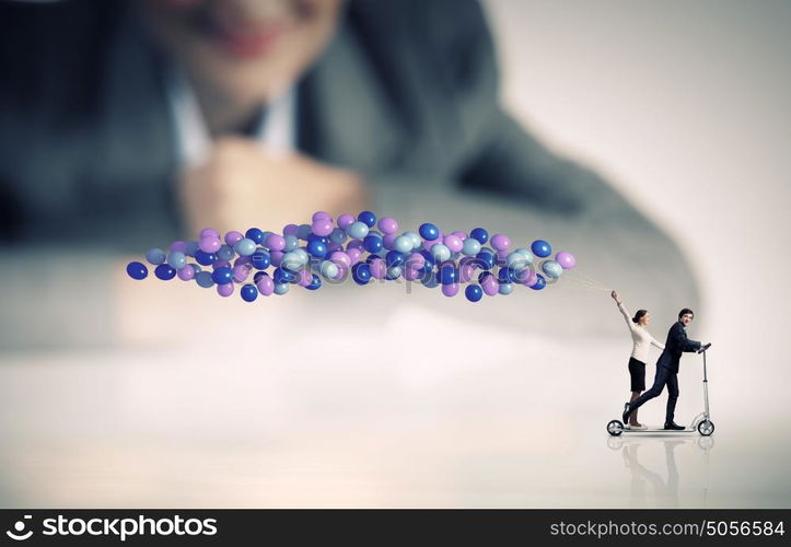 Business break. Businessman and businesswoman riding scooter with balloons in hand