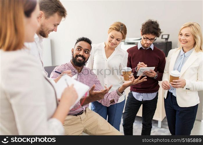 business, break, communication and people concept - happy creative team with notebooks drinking coffee and talking at office. happy business team drinking coffee at office