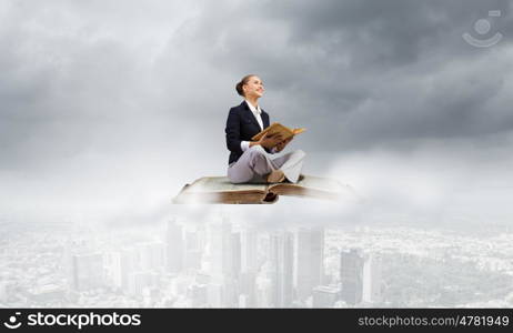 Business break. Young attractive businesswoman floating on old book and reading