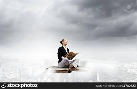 Business break. Young attractive businesswoman floating on old book and reading