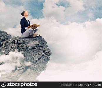 Business break. Young attractive businesswoman sitting on top of rock and reading