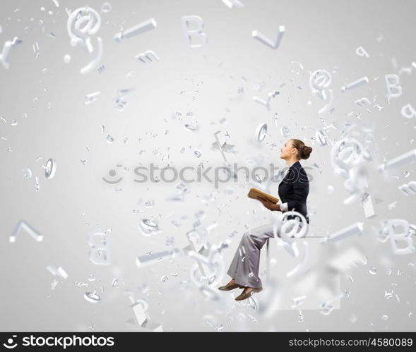 Business break. Young attractive businesswoman sitting on white cube and reading