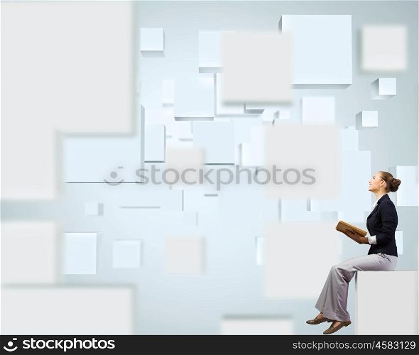 Business break. Young attractive businesswoman sitting on white cube and reading