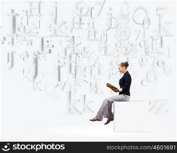 Business break. Young attractive businesswoman sitting on white cube and reading