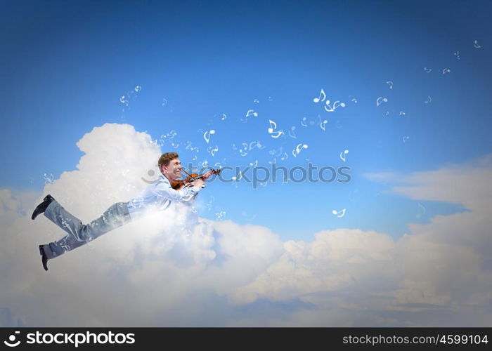 Business break. Young businessman flying high above city and playing violin