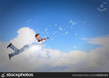 Business break. Young businessman flying high above city and playing violin