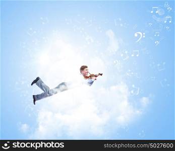 Business break. Young businessman flying high above city and playing violin