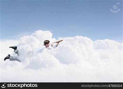 Business break. Young businessman flying in sky and lokking in spyglass