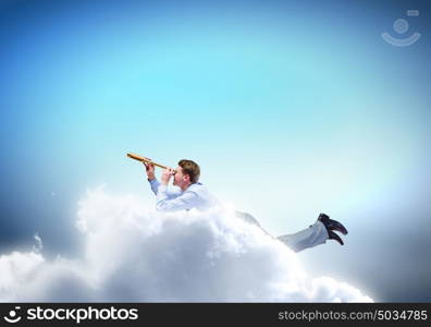 Business break. Young businessman flying in sky and lokking in spyglass