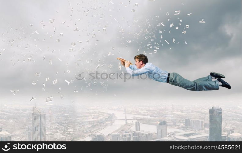 Business break. Young businessman flying in sky and playing fife