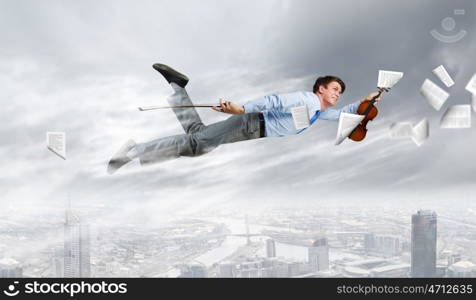 Business break. Young businessman flying in sky and playing fife