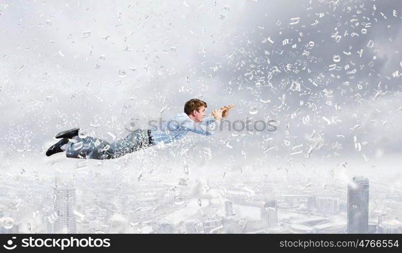 Business break. Young businessman flying in sky and playing fife