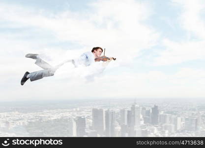 Business break. Young businessman flying in sky and playing violin