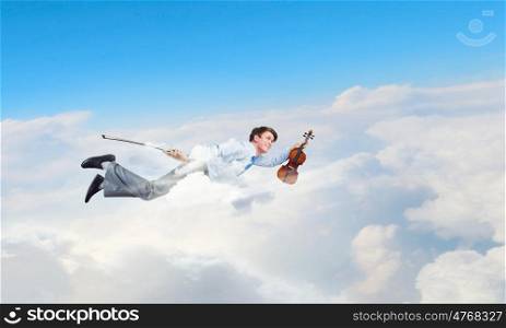 Business break. Young businessman flying in sky and playing violin