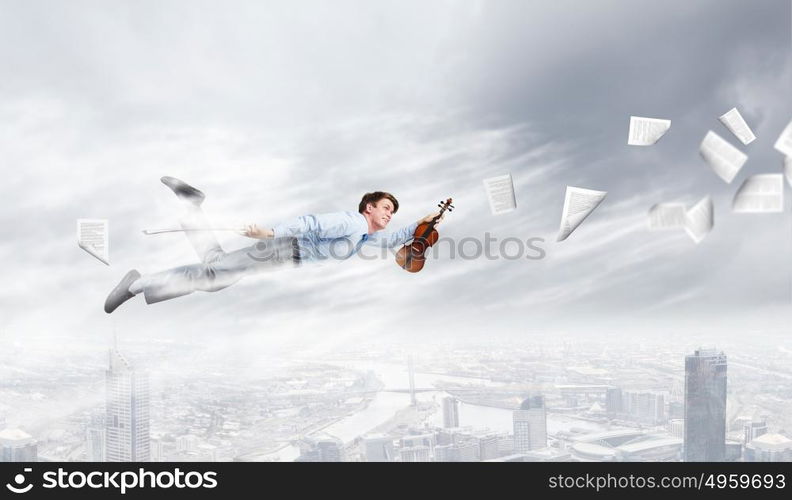 Business break. Young businessman flying in sky and playing violin