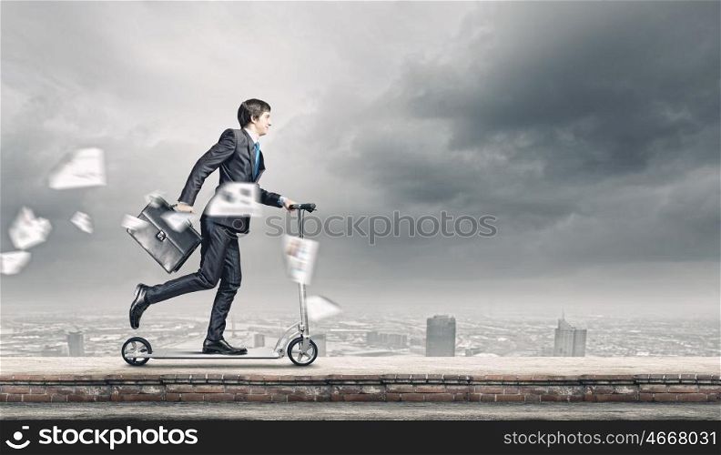 Business break. Young businessman riding scooter on roof of building