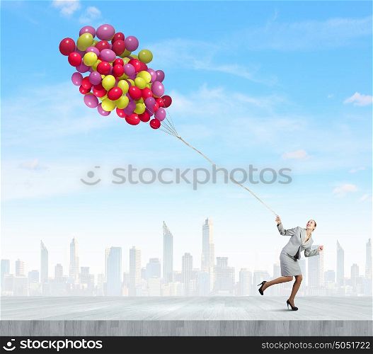 Business break. Young businesswoman running with bunch of colorful balloons