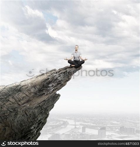Business break. Young businesswoman sitting on top of hill and meditating