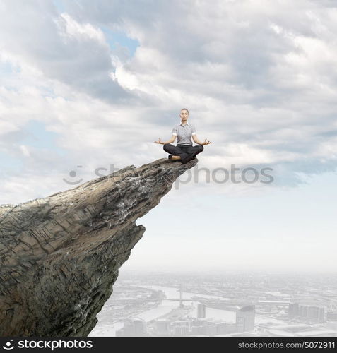 Business break. Young businesswoman sitting on top of hill and meditating