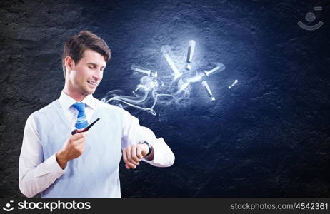 Business break. Young handsome businessman in fumes smoking pipe