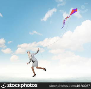 Business break. Young happy businesswoman running with colorful kite