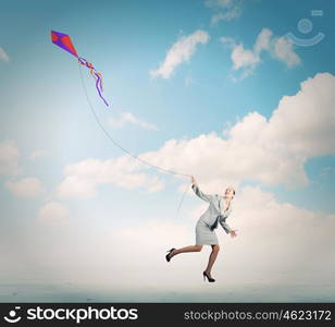 Business break. Young happy businesswoman running with colorful kite