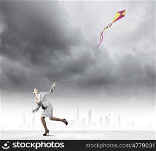 Business break. Young happy businesswoman running with colorful kite