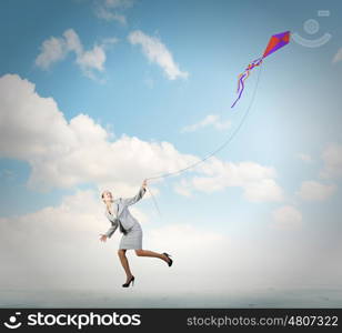 Business break. Young happy businesswoman running with colorful kite